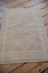 Distressed vintage Oushak rug mat showing subtle floral design in sand and cream tones.