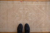 A close view of a distressed Oushak rug's low pile, showing even wear down to the knot heads.
