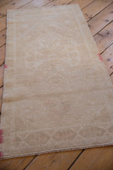 Distressed vintage Oushak runner seen from an angle, highlighting its even wear and muted beige tones.