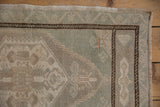 Distressed Vintage Oushak rug corner, meandering vine border in dusty seafoam, ivory, brown, original selvage.