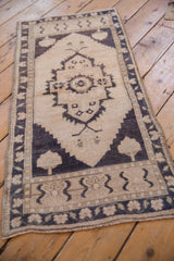 Detail of vintage distressed Oushak rug with worn ivory pile and dark geometric motifs.