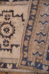 Distressed vintage Oushak rug close-up: ivory field patterns, even wear, and a dusty blue border.