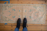 Distressed Oushak runner features cream and soft mint green arabesque motifs, showing wear.