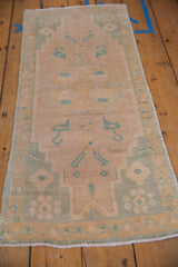 Distressed Oushak rug shows mint green germinating plant finial on a cream field.