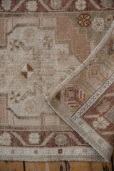 Stepped floral motifs on a distressed vintage Oushak rug pile with abrash and intact selvage.