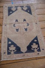 Distressed Oushak rug with even wear, featuring a muted beige and dusty navy floral design.