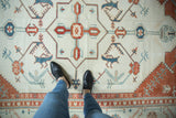 A view from above a distressed Oushak rug showing its terracotta and blue geometric design.