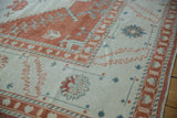 Evenly worn pile on a vintage Oushak rug with terracotta and blue serrated floral designs.