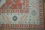 Distressed Oushak rug corner with terracotta and powder blue geometric and floral designs.