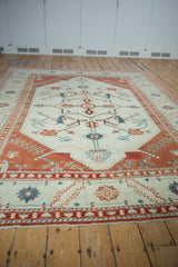 Perspective view down the length of a distressed Oushak rug with an ivory field and geometric pattern.