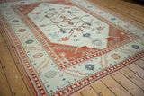 Angled view of a vintage distressed Oushak carpet in terracotta, ivory, and powder blue.