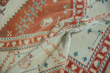 Softly folded Oushak rug showing its pliable wool weave and terracotta, blue, and ivory serrated motifs.