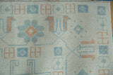 Distressed texture of a vintage Oushak's pile, featuring geometric motifs in sky blue and terracotta.