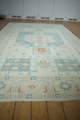 Full length perspective of a distressed Oushak rug with soft blue and terracotta geometric designs.