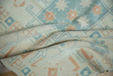 Textured pile of a distressed Oushak carpet with sky blue and terracotta starburst designs.