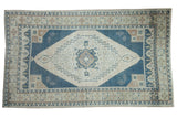 Distressed vintage Oushak carpet with a geometric shadow medallion in dusty denim blue, ivory, and pale coffee brown.