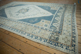 Angled view of a distressed Oushak rug's geometric border and serrated corner spandrel.