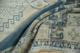 Folded corner of a Turkish Oushak showing geometric blossom border motifs in dusty blue and beige.