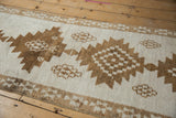 Serrated-edge geometric medallions in coffee brown on the short, hand-knotted ivory pile.