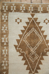 Close-up of the short, hand-knotted pile with a serrated geometric medallion in brown and ivory.