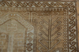 Distressed Oushak rug: geometric medallion detail with ram's horn motifs in beige and coffee brown.