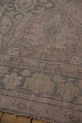 Worn pile of distressed hand knotted Oushak rug, showing muted pink and beige geometric motifs.