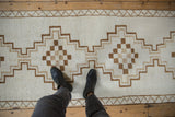A person's view of the distressed Kars runner's short pile and stepped geometric pattern.