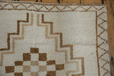 Corner of a vintage Kars rug with stepped line and checkered patterns in brown and ivory.