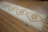 Angled view of a vintage Kars rug runner showcasing its column of stepped geometric medallions in earthy tones.