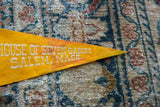 Close-up of the white text and visible patina on the vintage yellow felt flag.