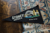 Vintage Sydney Australia felt pennant with a painted Harbour Bridge graphic shown at an angle.