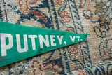 Green felt pennant tip with white 'PUTNEY, VT' lettering and folded edge.