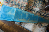 Close-up of the vintage blue felt pennant's underside, revealing its aged texture and varied tones.