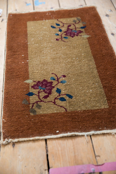 Angled view of a vintage Nichols Art Deco rug showing its floral vinery and copper border.