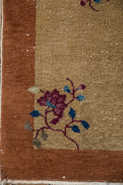 Corner detail of a Nichols Art Deco rug showing floral vinery and mostly even pile wear, size 1'6