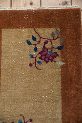 Corner detail of a vintage Nichols rug showing mostly even wear and exposed foundation.