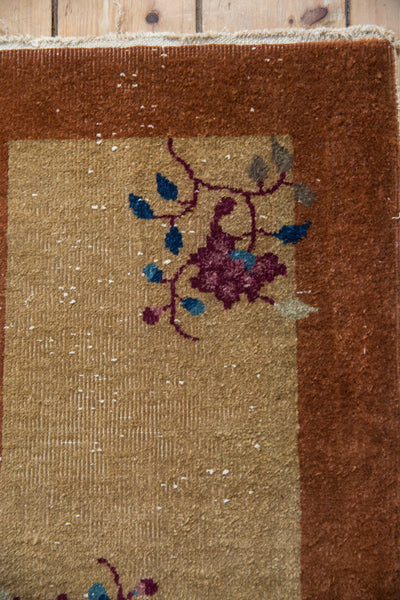 Corner detail of a vintage Nichols rug showing mostly even wear and exposed foundation.