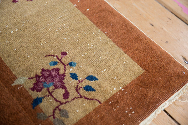 Corner detail of a vintage Nichols rug showing floral vinery and mostly even pile wear.