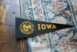 Vintage black felt pennant with gold IOWA lettering and detailed university seal.
