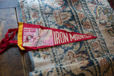 Angled view of the vintage 'Iron Mountain' red felt flag with its miner graphic.
