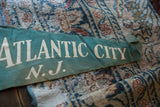 Vintage green felt flag showing 'ATLANTIC CITY N.J.' text and age-related marks.