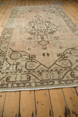 Distressed vintage Oushak rug field with pale blush, beige, and potted tree motifs.