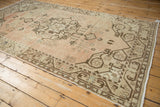 Distressed vintage Oushak rug, with worn pale blush field and patterned beige border.