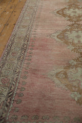 Decorative geometric vine border with ivory, bronze patterns on a distressed faded rose Oushak runner.