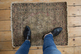 Worn pile texture and faded cochineal red floral motifs on an antique Kerman rug.