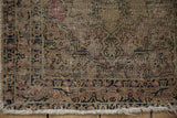 Aged pile, tattered ivory fringe, and navy floral border detail on an antique Kerman rug.