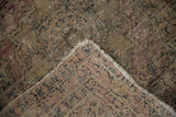 Antique Kerman rug's worn pile revealing foundation, tattered edges, and hand-knotted reverse.