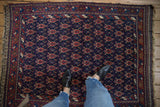 Overhead view of an antique Afshar rug's repeating turtle design in navy blue and madder red.