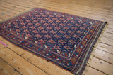 Angled view of an antique Afshar rug showing the full geometric pattern and detailed vine border.