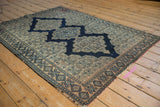Antique Senneh rug with intricate Herati motif, navy scalloped medallion contour, and worn edge.